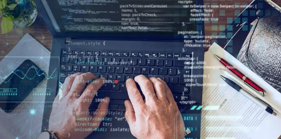 Programista pracujący na laptopie z widocznym kodem na ekranie, otoczony dokumentami i piórami. Ilustracja symbolizuje praktyczne zastosowanie Node.js w programowaniu i tworzeniu aplikacji.